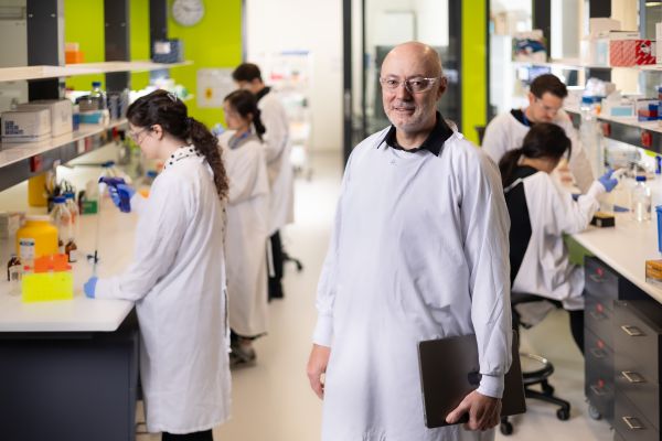 Man standing in lab in front of team working at benches