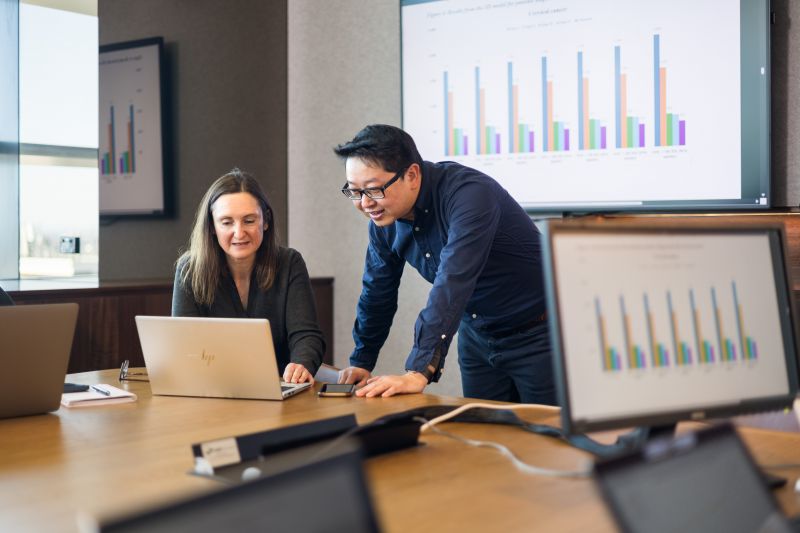 Two people talking in front of graphs